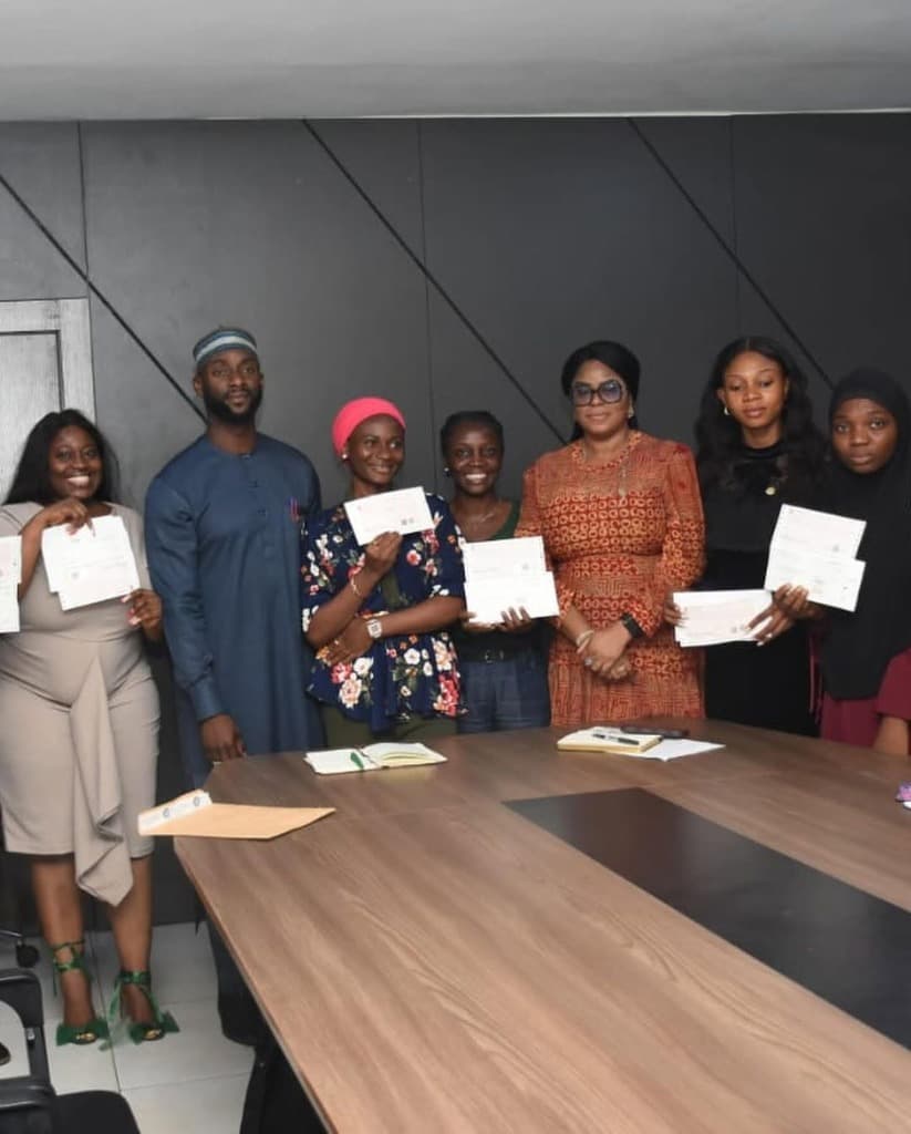 Female and youth entrepreneurs holding grant awards and certificates in executive session